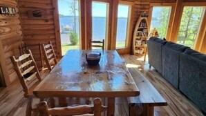 Una cabaña de madera con una gran mesa de comedor, sillas y un sofá.