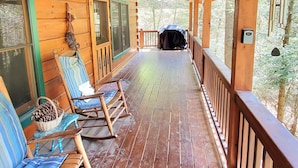 Eine hölzerne Veranda mit Schaukelstühlen und Deckenventilator.