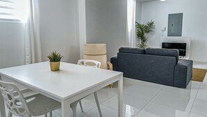 Un salon moderne avec une table blanche, un canapé gris et un meuble pour la télévision.