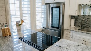 A modern kitchen with a stainless steel refrigerator, a built-in oven, and a granite countertop.