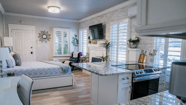 A modern kitchen with a built-in stove, a dining area with a bench, and a cozy seating area with a sofa and a fireplace.