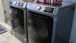 Two front-loading washing machines with a small plant and folded towels on top.