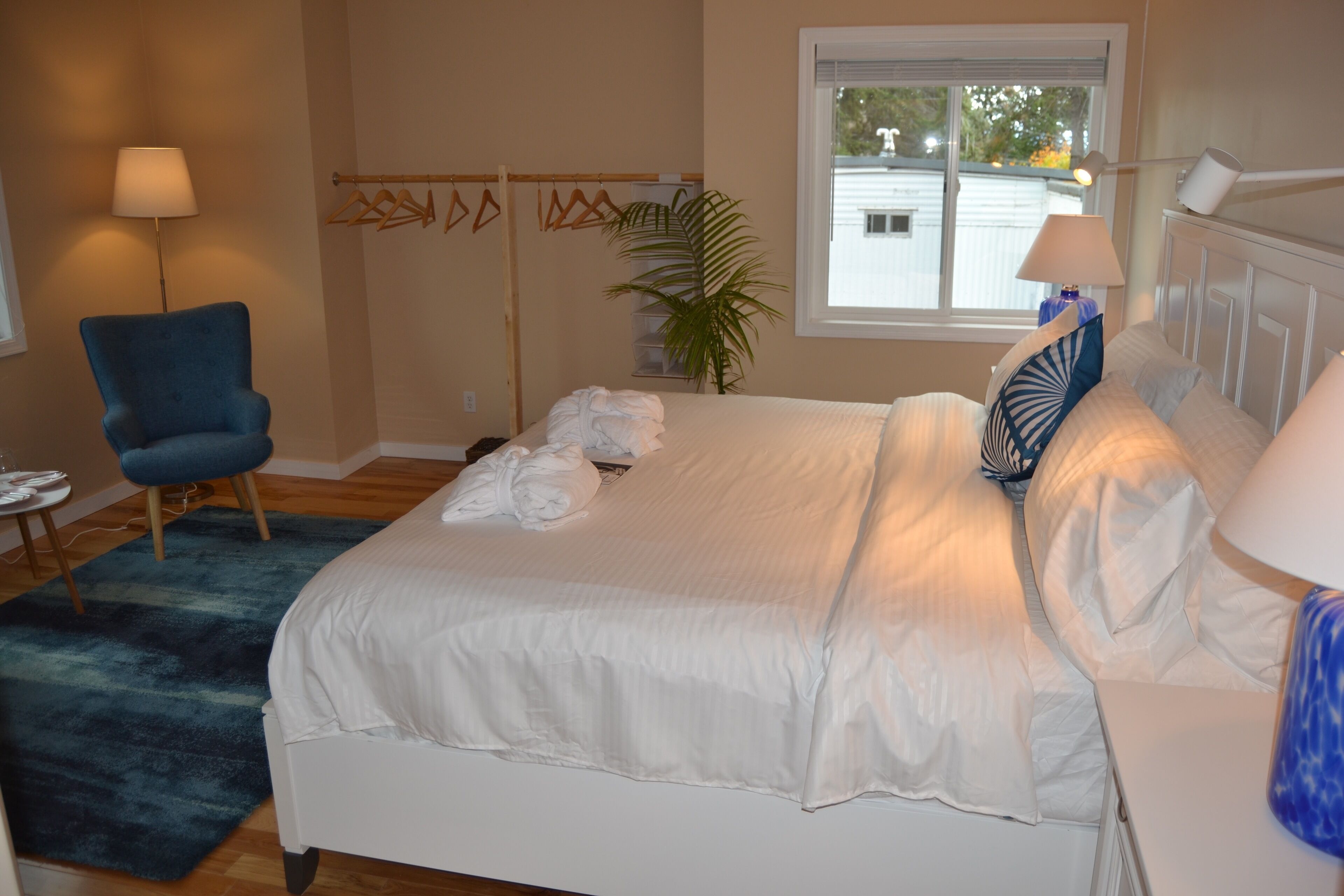 A bedroom with a bed, a chair, a lamp, and a window.