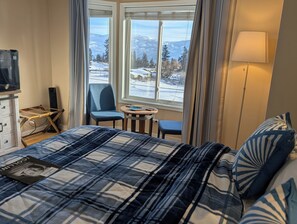 Una habitación de hotel con una cama, una silla, una mesita y un televisor.