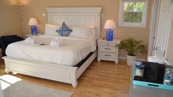 A neatly arranged bedroom with a large bed, bedside lamps, a potted plant, and a coffee maker on a table.