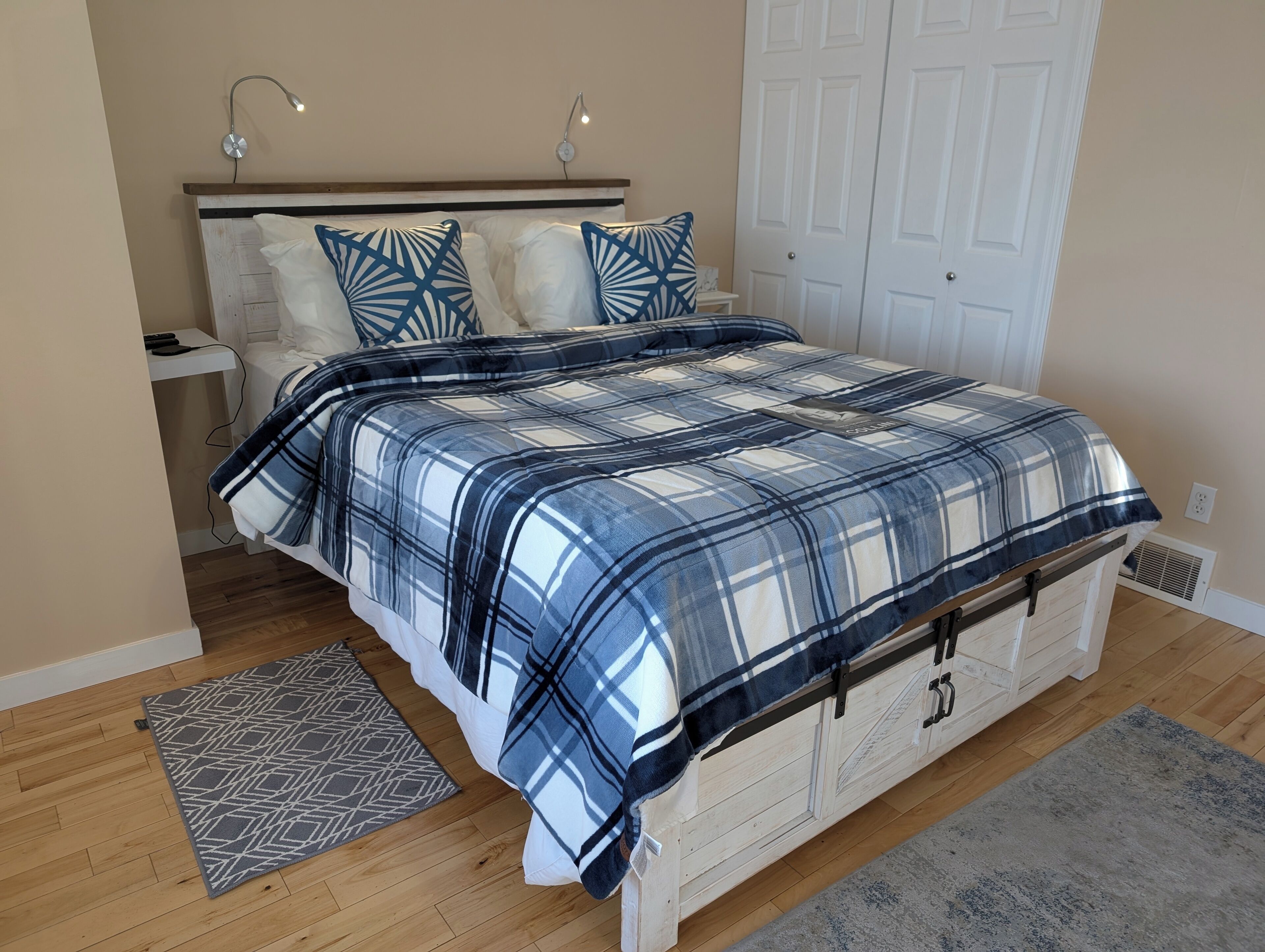 Una camera da letto con un letto, lampade da comodino, un tavolino e un tappeto decorato, oltre a una porta.