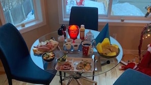 Comedor con mesa preparada para cuatro personas, rodeada de sillas, y vista a un paisaje nevado a través de amplios ventanales.