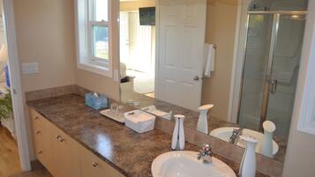 A bathroom with a granite countertop, a white sink, a mirror, and a glass shower enclosure.