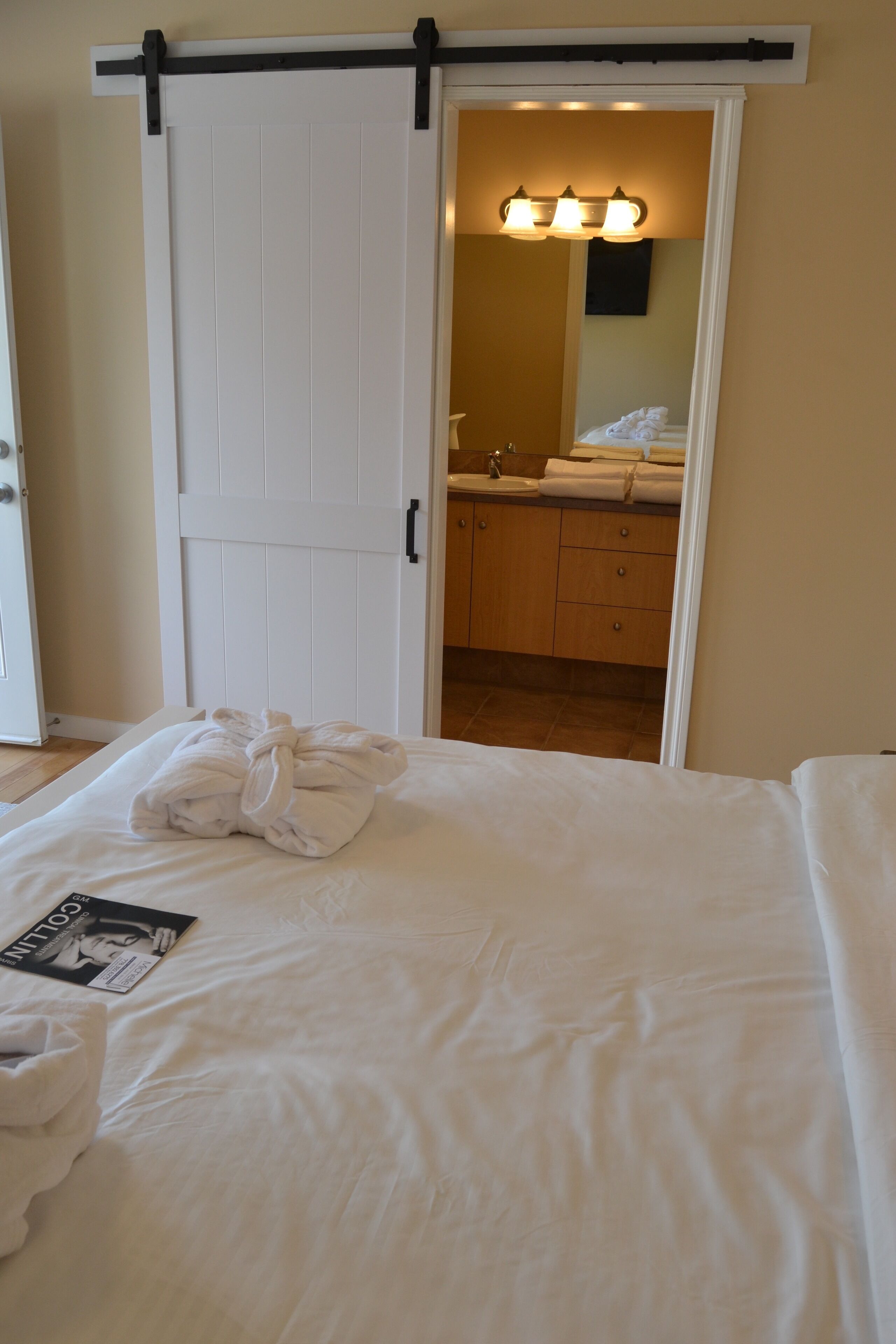 Quarto de hotel com cama, banheiro visível através de uma porta aberta e uma toalha sobre a cama.