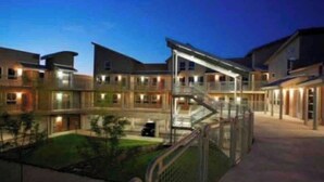 A multi-story building with a central courtyard, balconies, and a staircase leading to an upper level.
