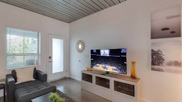 A modern living room with a flat-screen TV, a sofa, a coffee table, and a decorative mirror.