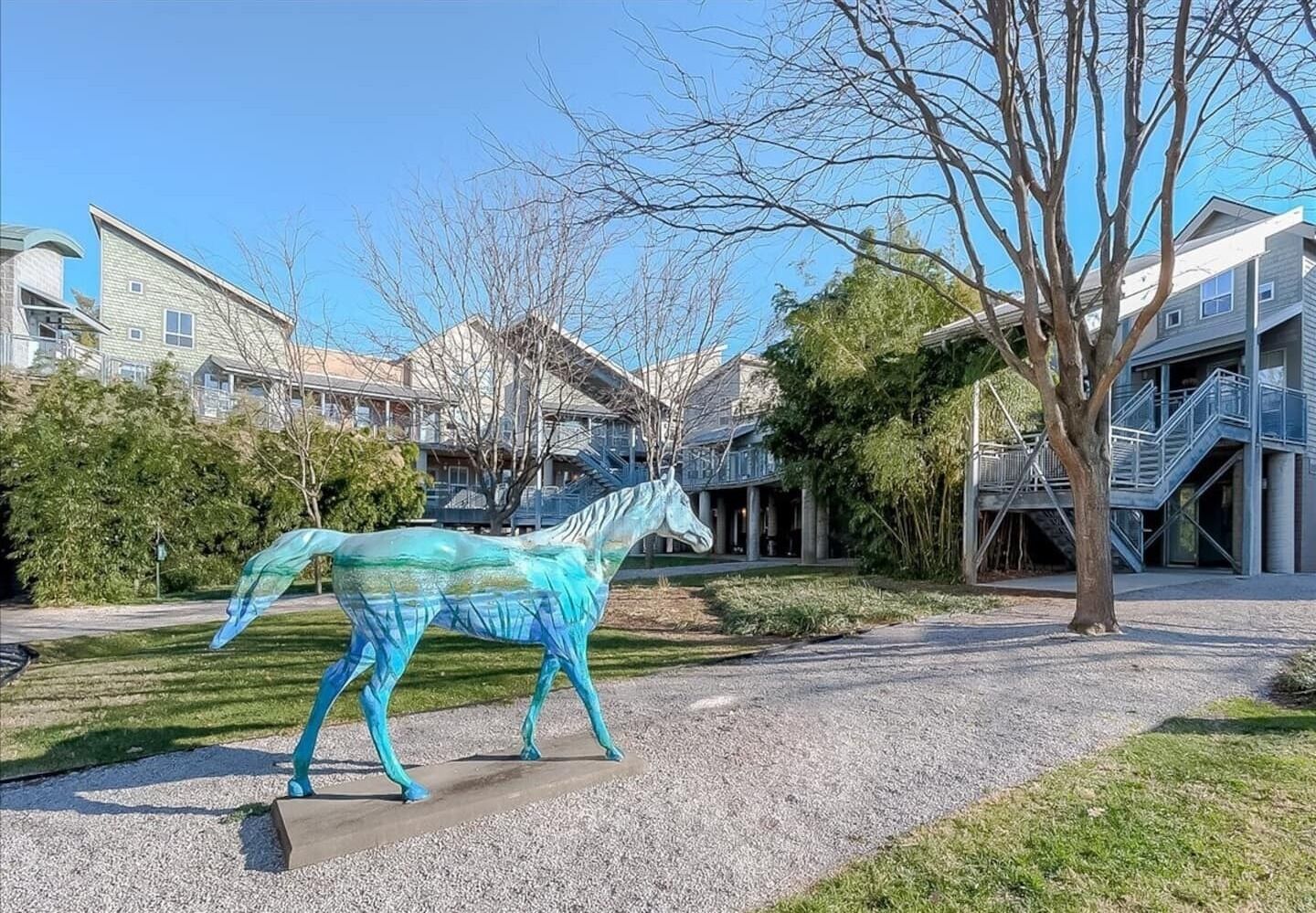 Une sculpture de cheval se trouve dans un parc, avec des immeubles d’habitation en arrière-plan.