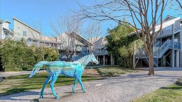 Une sculpture de cheval se trouve dans un parc, avec des immeubles d’habitation en arrière-plan.