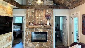 A cozy living room with a stone fireplace, wooden beams, and a comfortable seating area.