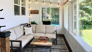 A cozy living room with a sectional sofa, a coffee table, and a large window offering a view of the outdoors.