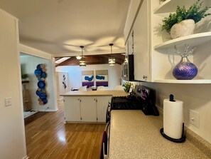 A modern kitchen with wooden cabinets, a gas stove, and pendant lighting.