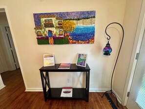 Une pièce avec une table noire sur laquelle sont posés des livres, et une œuvre d’art encadrée au-dessus.