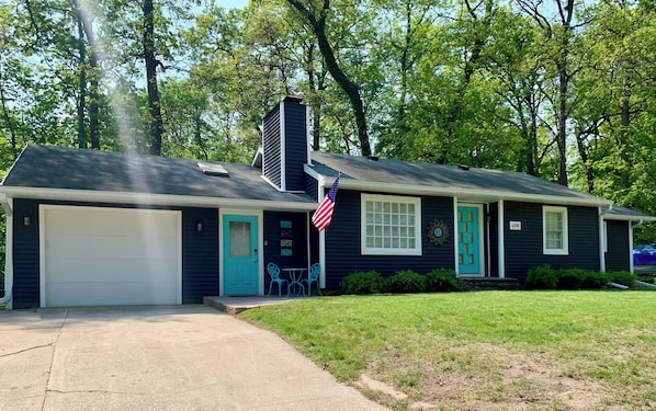 Einbungalow mit Garage, einer Veranda mit kleinem Tisch und Stühlen und einer amerikanischen Flagge.