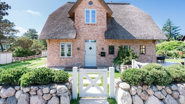 A brick house with a thatched roof, a white door, and a small porch. - Loddis Hüs - Loddi's Hüs (Wenningstedt-Braderup (Sylt))