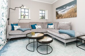 A modern living room with a grey sectional sofa, two round coffee tables, and a large beach-themed painting on the wall. - Loddis Hüs - Loddi's Hüs (Wenningstedt-Braderup (Sylt))