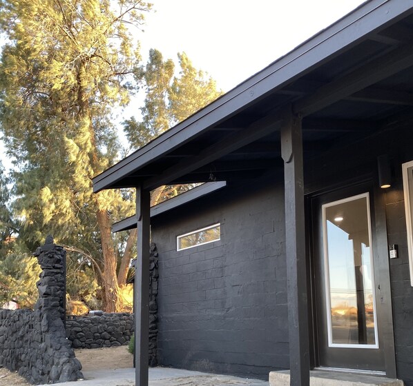 A modern building with a dark facade, stone pillar, and a covered entrance area.