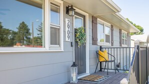 A house with a grey exterior, a number '2909' on the door, a small porch with a yellow chair, and a lantern.