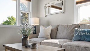 A living room with a sofa, a coffee table, a lamp, and a vase with flowers.