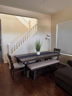 A dining area with a wooden table, benches, and a potted plant.