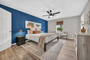 Un dormitorio con cama, mesitas de noche, un escritorio y una silla.