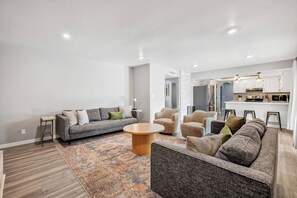 Una sala moderna con un sofá gris, una mesita redonda y dos sillones.
