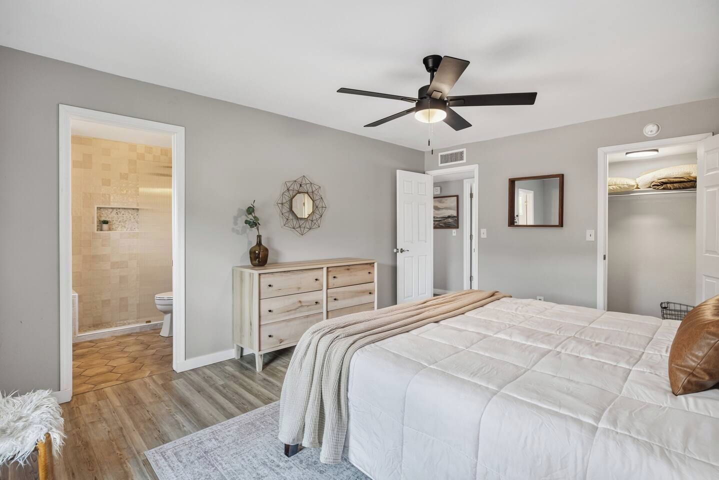 Un dormitorio con cama, cómoda y ventilador de techo.