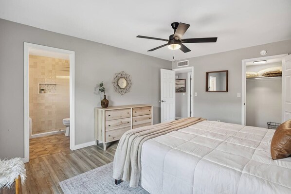 A bedroom with a bed, dresser, and a ceiling fan.