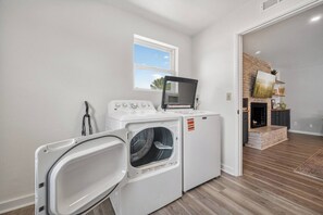 A laundry room with a washer and dryer, a window, and a fireplace in the adjacent living area.