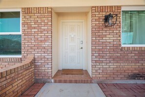 A house entrance with a white door, brick walls, and a small porch area.