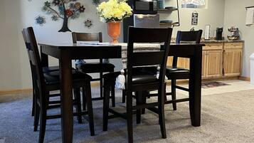 A dining area with a table and chairs, a vase with flowers, a microwave, and a coffee maker on the counter.