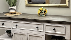 Un mueble blanco de madera con cajones y un espejo encima.