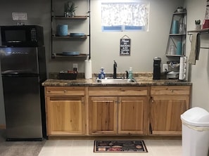 Kitchen area with refrigerator, microwave, and sink, equipped with cabinets and a countertop.