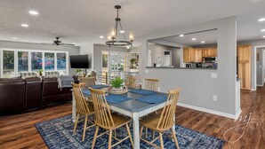 A spacious dining area with a large table, wooden chairs, and a chandelier. - 🌊Lakefront Hot Tub🛶Kayaks🔥Firepit🏖️Nature Lovers🦅Peaceful waterfront deck (Bull Shoals)