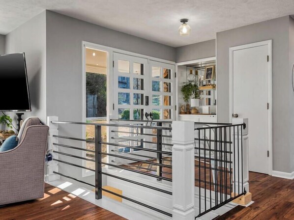A modern interior with a staircase, a flat-screen TV, and a dining area with a view. - 🌊Lakefront Hot Tub🛶Kayaks🔥Firepit  🏖️Nature Lovers🦅Peaceful waterfront deck (Bull Shoals)