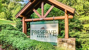 A wooden sign with the text "The Preserve Resort" against a backdrop of lush greenery and a stone wall. - SPRING DISCOUNTS! Hot Tub ⭐️ AMAZING VIEWS⭐️ Games 🎱 🐻 (Sevierville)