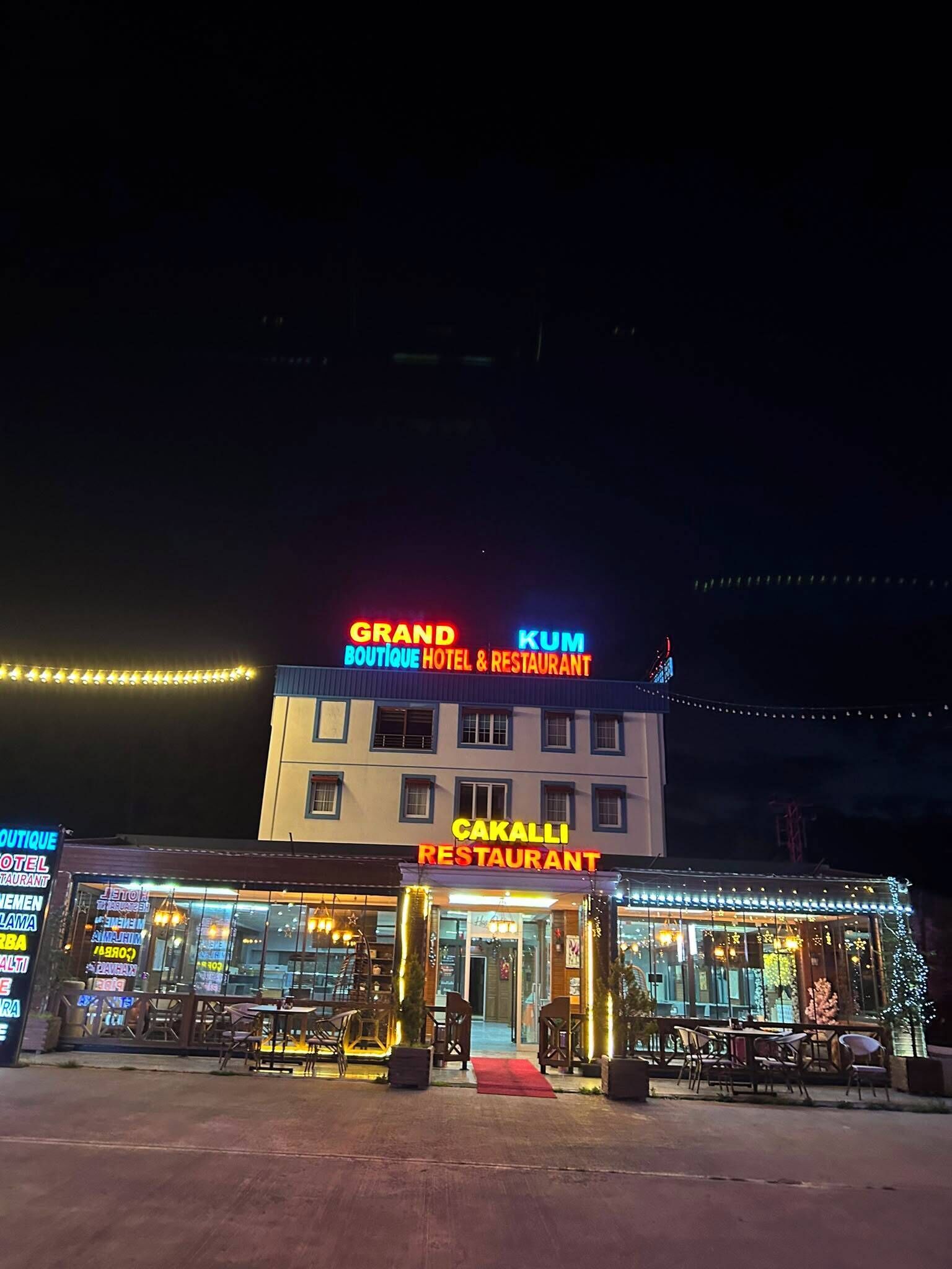 A hotel with a prominent sign for 'Grand Boutique Hotel & Restaurant' and 'Cakalli Restaurant' at night.