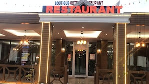 A restaurant with a modern facade, large glass windows, and a sign indicating it is a 'Boutique Hotel Restaurant'.