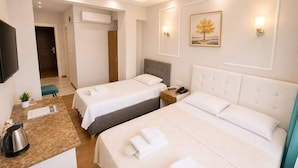 A hotel room with two beds, a TV, a coffee maker, and a painting on the wall.