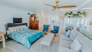 A modern bedroom with a bed, a desk, a sofa, and a ceiling fan. - Luxury Beachfront Condo with Ocean View (Hauula)