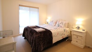 Una camera da letto con un letto, comodini, una sedia e una finestra.
