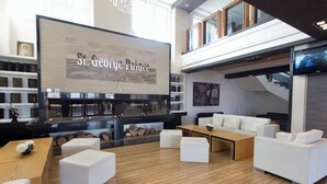 Ein modernes Interieur mit einem großen Schild mit der Aufschrift "St. George Palace", Holzboden, weißen Sofas und einem Kamin.