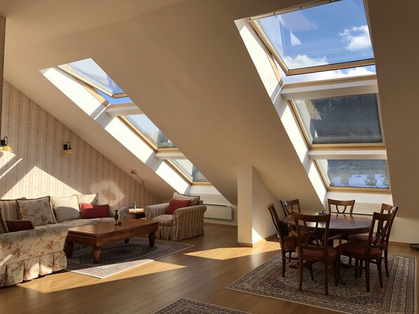 Un loft spacieux doté de fenêtres de toit, d’un canapé, d’une table à manger et de chaises.