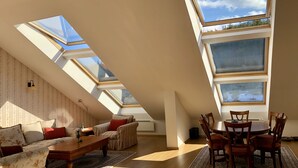 Ein geräumiges Loft mit Dachfenstern, einer Couch, einem Esstisch und Stühlen.