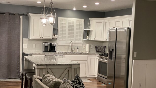Una cocina moderna con muebles blancos, un refrigerador de acero inoxidable y una isla integrada con asientos.