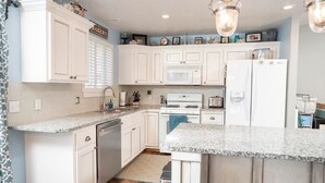 Una cocina con armarios blancos, microondas, estufa y refrigerador.